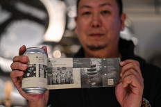 This photo taken on November 20, 2020 shows Wang Fan, founder of the No. 18 Brewery, posing with one of his beers with images of the city's fight against the COVID-19 coronavirus in Wuhan, China's central Hubei province. 