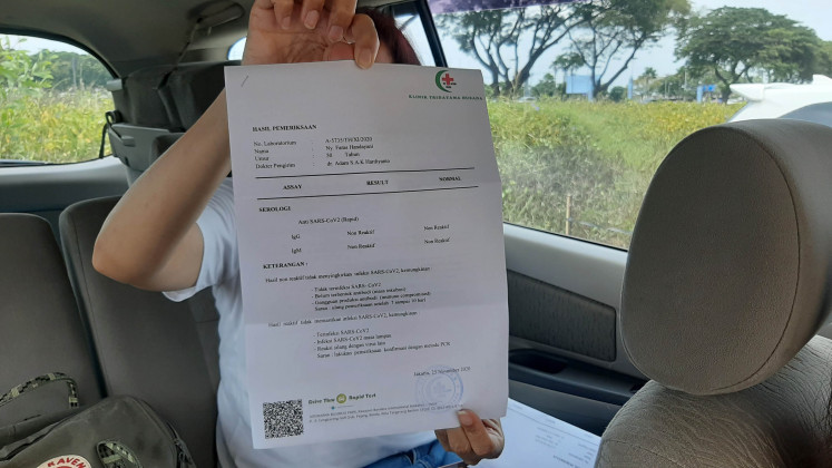 Nonreactive result: Shortly after taking a rapid antibody test at a drive-thru station at Soewarna Business Park in Tangerang, Banten, a would-be airline passenger shows her test result. Included in the document is a doctor’s note and recommendations.