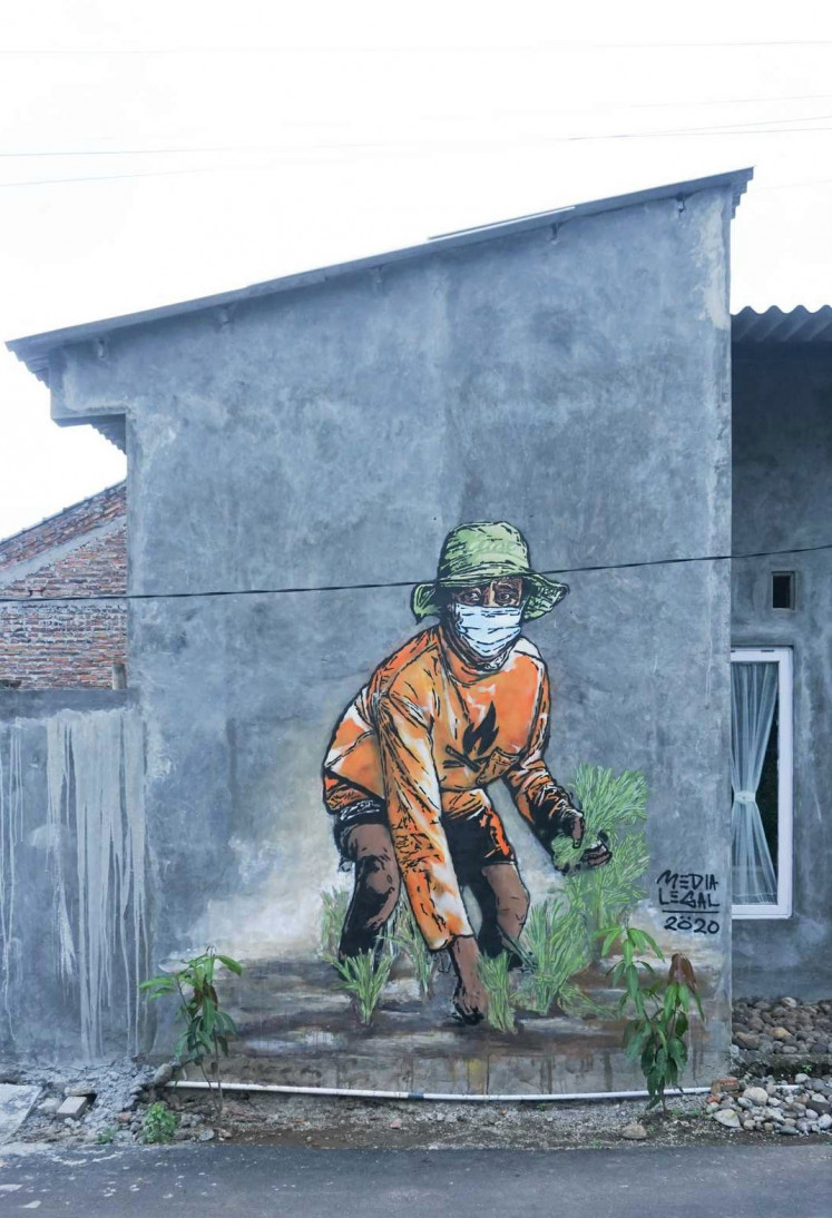 Safe farming: A mural shows a farmer planting paddy seedlings on a house wall in Kampung Sendangguwo. The mural, part of the biennial art project Penta Klabs by the artist collective Kolektif Hysteria, was displayed virtually at the National Gallery of Indonesia’s digital exhibition platform.