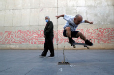 A man looks at Bulgarian street skateboarder Petar 'Stewie' Stantchev, 25, doing a trick, known as an ollie, in front of MACBA (Barcelona Contemporary Art Museum), amid the coronavirus disease (COVID-19) outbreak, in Barcelona, Spain, on November 11, 2020. 