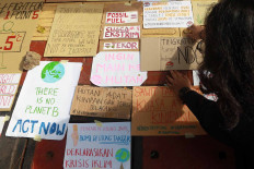 Civil groups place signs outside the Environment and Forestry Ministry building in Jakarta on Dec. 11 to demand that the government commit to reducing greenhouse gas emissions. Experts have urged countries to reduce their emissions further to limit the global temperature rise to below 2 degrees Celsius. JP/Dhoni Setiawan