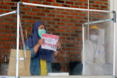 A COVID-19 patient (left) casts her ballot as a health officer wearing personal protective gear looks on at a COVID-19 isolation facility that was treating 49 voters in South Tangerang, Banten, on Dec. 9. JP/Dhoni Setiawan
