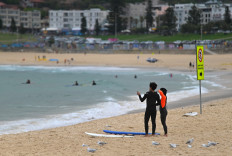Surfers stand at Bondi Beach where a COVID-19 drive-through testing center has been set up, in Sydney on Dec. 20, 2020.
