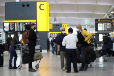 Travelers wearing a face mask or covering due to the COVID-19 pandemic, stand at check-in desks at Terminal 2 of Heathrow Airport in west London on December 21, 2020, as a string of countries around the world banned travelers arriving from the UK, due to the rapid spread of a new, more-infectious coronavirus strain. 