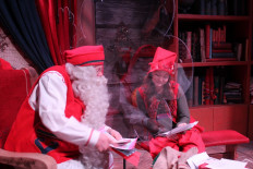 Santa and his elf, Vanilla, read letters separated by a plexiglass screen to slow the spread of coronavirus, on December 17, 2020 in Rovaniemi at the Santa Claus Village amusement park, where visitor numbers have collapsed this year due to coronavirus restrictions. 