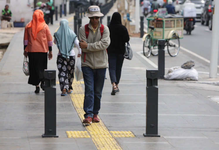 Solitary stroller: A man walks alone on a sidewalk in Cikini, also in Central Jakarta.