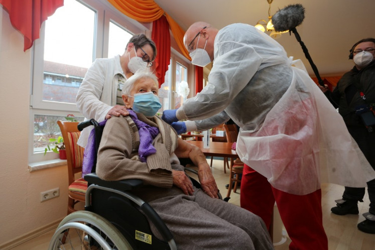 Edith Kwoizalla, 101 years old, receives the first vaccination against the novel coronavirus COVID-19 by Pfizer and BioNTech from Doctor  Bernhard Ellendt (R) in a senior care facility in Halberstadt (Seniorenzentrum Krueger), central northern Germany, on December 26, 2020. - The European Union began a vaccine rollout, even as countries in the bloc were forced back into lockdown by a new strain of the virus, believed to be more infectious, that continues to spread from Britain. The pandemic has claimed more than 1.7 million lives and is still running rampant in much of the world, but the recent launching of innoculation campaigns has boosted hopes that 2021 could bring a respite. 