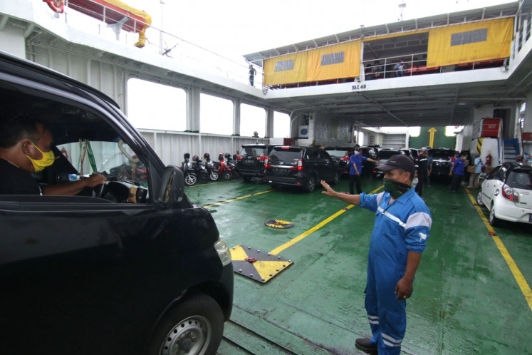 A port worker (right) gestures to a van at the Ketapang Port in Banyuwangi, East Java, on Dec. 27, 2020. According to government data, the Ketapang-Gilimanuk ports saw 31,932 travelers and 6,854 vehicles in the run-up to the Christmas and New Year holidays. 