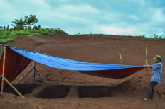 A gravedigger works at newly dug graves at a public cemetery in Sukamulya village in Ciamis, West Java, on Friday. The Ciamis regency administration provides graves for COVID-19 patients who die from the coronavirus. 
