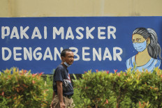 A man not properly wearing his face mask passes a banner for a face mask-wearing campaign displayed at Depok City Hall in West Java on Wednesday.
West Java Governor Ridwan Kamil has announced that Depok and Karawang are on high alert for the spread of COVID -19.