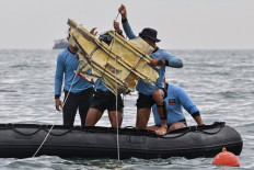Indonesian Navy divers hold wreckage from Sriwijaya Air flight SJY182 during a search and rescue operation at sea near Lancang island on January 10, 2021, after the Boeing 737-500 crashed shortly after taking off from Jakarta airport on January 9.
