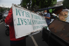 Security officers dismantle signage belonging to the Islam Defenders Front (FPI) as they close down the hard-line group's headquarters in Petamburan, Central Jakarta, on Dec. 30, 2020, after its official disbandment by the government. 