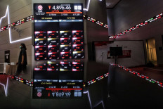 Up and down: A visitor walks past an electronic board showing the movement of the Indonesian Composite Index at the Indonesia Stock Exchange building in Jakarta on Sept. 10, 2020. The pandemic has led to a significant rise stock trading, with about 488,000 new trading accounts registered in 2020, marking a 93 percent annual increase.