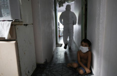 A kid looks on as a municipal healthcare worker walks after examining the body of Shirlene Morais Costa, who died at home at the age of 53 after reporting symptoms consistent with COVID-19, amid the coronavirus disease (COVID-19) outbreak in Manaus, Brazil, January 11, 2021. Picture taken January 11, 2021. 