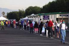 People wait in line to receive the COVID-19 vaccine at a mass vaccination site in a parking lot for Disneyland Resort on January 13, 2021 in Anaheim, California. California announced that effective immediately, all residents 65 or older are eligible to receive the vaccine. 