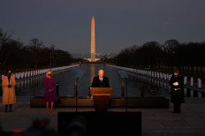 US President-elect Joe Biden looks down as he speaks, flanked by US Vice President-elect Kamala Harris (left), his wife Dr. Jill Biden and Cardinal Wilton Gregory, Archbishop of Washington (right), during a Covid-19 Memorial at the Lincoln Memorial in Washington, DC, on January 19, 2021 to honor the lives of those lost to Covid-19. 