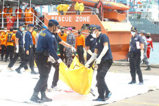 Tough duty: Personnel of the National Police’s disaster victim identification unit carry a bag containing the body of a victim of the Sriwijaya Air SJ182 crash at the Jakarta International Container Terminal’s quay in Tanjung Priok, North Jakarta, on Jan. 12. 