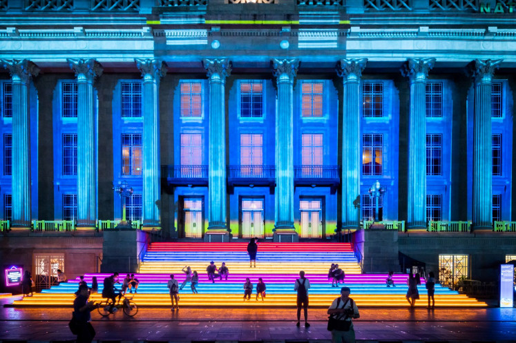 Bright night: People sit on the steps of the National Gallery Singapore, in front of its illuminated facade. The Light to Night Festival will be the marquee event of Singapore Art Week 2021. 