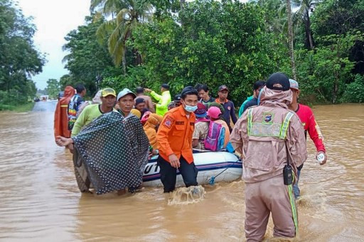 This handout photo taken and released on Jan. 15 by the Indonesian National Board for Disaster Management (BNPB) shows rescuers evacuating villagers by rubber boat in a flooded area in the Tanah Laut districts, South Kalimantan.
