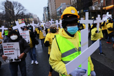 People hold up signs and crosses as they participate in the "Left to Die" march on January 26, 2021 in New York City, US, calling for economic relief and immigration reform after feeling left out of government efforts during the coronavirus (COVID-19) pandemic.