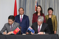 Vietnam's Prime Minister Nguyen Xuan Phuc (top left) and New Zealand Prime Minister Jacinda Ardern (top center) watch as Tran Tuan Anh (front left), Vietnam's Deputy Minister of Industry and Trade, signs a trade agreement with New Zealand's Minister of Agriculture Damien O'Connor at Government House in Auckland on March 13, 2018. 