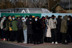 People wait to board shuttle buses to a COVID-19 coronavirus vaccine center in Beijing on January 4, 2021, as China races to innoculate millions before the Chinese New Year mass travel season in February. 
