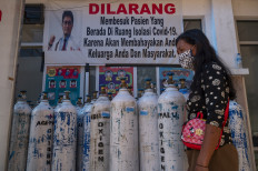 A visitor walks in front of oxygen tanks at Anutapura hospital in Palu, Central Sulawesi on Saturday.