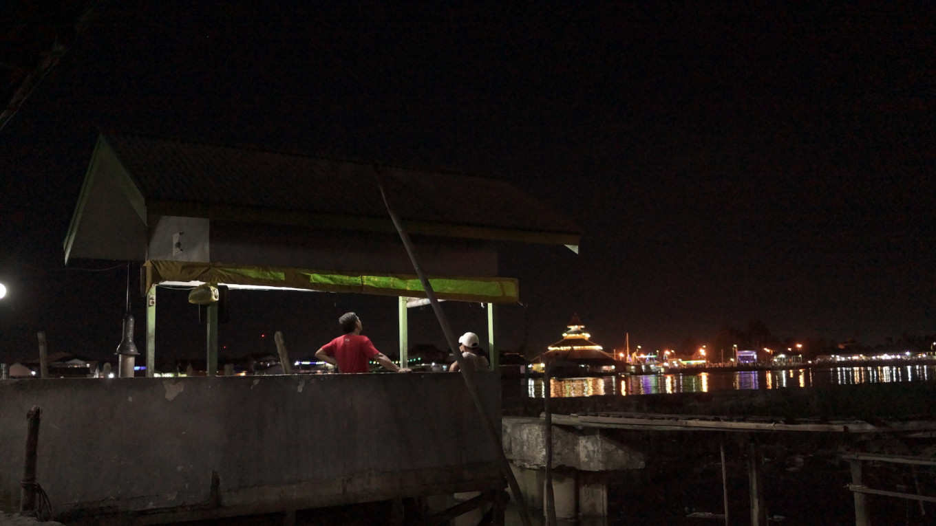 The party rarely stops: Late into midnight, two Beting residence wait at a post where they'll take visitors to the village by boat.