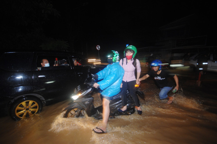 Motorists pass through the flood in Manado, North Sulawesi on Jan. 22. Torrential rains have inundated several areas in the city.
