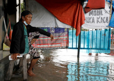 A man sits on a bench in an area affected by floods in Jakarta, in February 8, 2021.