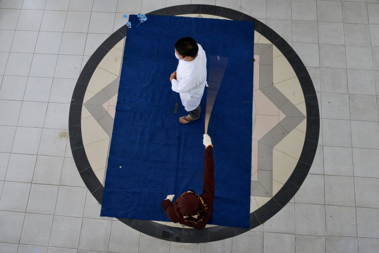 A Christian man is publicly caned by a member of the Sharia police, after he was caught gambling, in Banda Aceh on February 8, 2021.