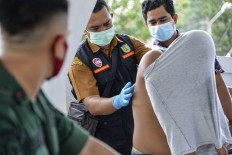Medical workers treat a Christian man's wounds on his back after being flogged by a member of the Sharia police for being caught gambling in Banda Aceh on February 8, 2021.