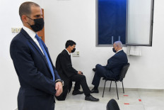 Israeli Prime Minister Benjamin Netanyahu (R) talks to his lawyer ahead of a hearing in his corruption trial at the Jerusalem district court, on February 8, 2021. Israel's Prime Minister Benjamin Netanyahu denied corruption charges against him in a brief court appearance, as his graft trial intensifies weeks before a fourth national election inside two years.