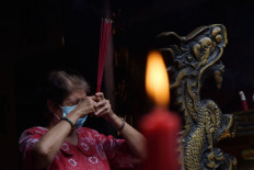 A woman prays at the Hwie Ing Kiong Tri Dharma Temple in Madiun, East Java on Feb. 12, 2021. The temple has changed the prayer schedule from midnight to noon during the micro-scale public activity restrictions (PPKM Mikro) to curb COVID-19 transmission during the holiday period.