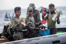 Piece by piece: Indonesian Navy divers hold up pieces of debris recovered off the northern coast of Jakarta on Jan. 12 during recovery operations for Sriwijaya Air flight SJ182, which crashed shortly after takeoff from the capital on Jan. 9 with 62 people onboard. 