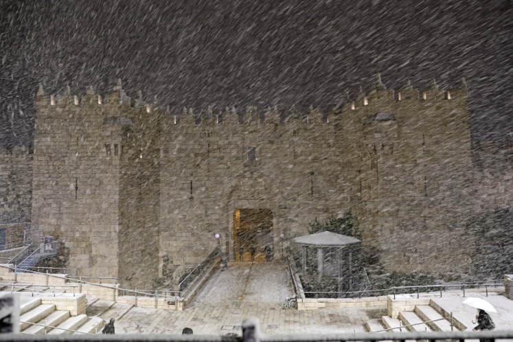 Snow falls at the Damascus Gate in Jerusalem's Old City, on February 17, 2021.
