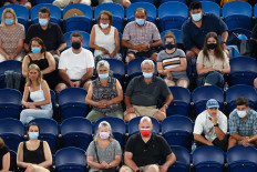 Fans wearing face masks watch Serbia's Novak Djokovic play against Russia's Aslan Karatsev during their men's singles semi-final match on day eleven of the Australian Open tennis tournament in Melbourne on February 18, 2021. 