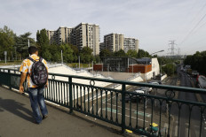 In this file photo taken on Sept. 2, 2016, a pedestrian walks across a footbridge in Grigny 2 district near the central station of Grigny, south of Paris. In Grigny, a city in the south of Paris classified as the poorest in France, the Covid-19 pandemic provoked an 