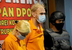 Andrey Kovalenko (center), a Russian man wanted by Interpol, and Russian national Ekaterina Trubkina (left) stand during a press conference at Imigration Ngurah Rai office in Jimbaran on Indonesia resort island of Bali on February 24, 2021. 