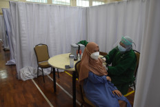 A vaccinator inoculates a Corruption Eradication Commission (KPK) employee with the COVID-19 vaccine at the antigraft body headquarters in Jakarta on Feb. 23, 2021.