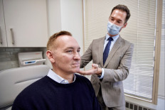 Plastic surgeon Dr. Michael Somenek examines the face of his patient Hudson Young, 52, who had a lower face and neck lift, an upper and lower eyelid surgery and laser resurfacing done in October 2020, in Dr. Somenek’s clinic in Washington, DC on February 22, 2021. 