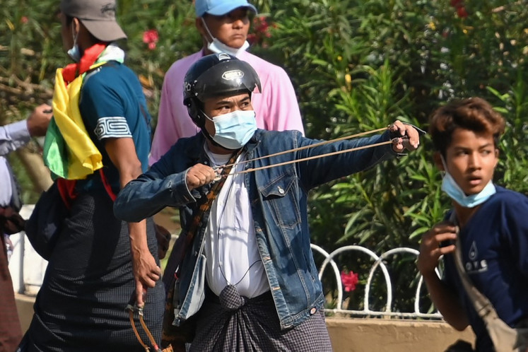 A pro-military supporter uses a sling-shot to fire projectiles at residents during a rally in Yangon on February 25, 2021, following weeks of mass demonstrations against the military coup. 