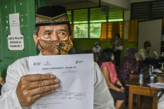 A man shows his COVID-19 vaccination card at a state elementary school in Penggilingan, North Jakarta, on Feb. 25. Indonesia is targeting to inoculate some 21 million people aged 60 and above and 17 million public service workers in the second phase of the vaccination program, which started on Feb. 17.