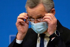 NATO Secretary General Jens Stoltenberg removes his protective face mask during a press conference following a video conference with NATO Defence Ministers, at the NATO headquarters in Brussels on Feb. 18.