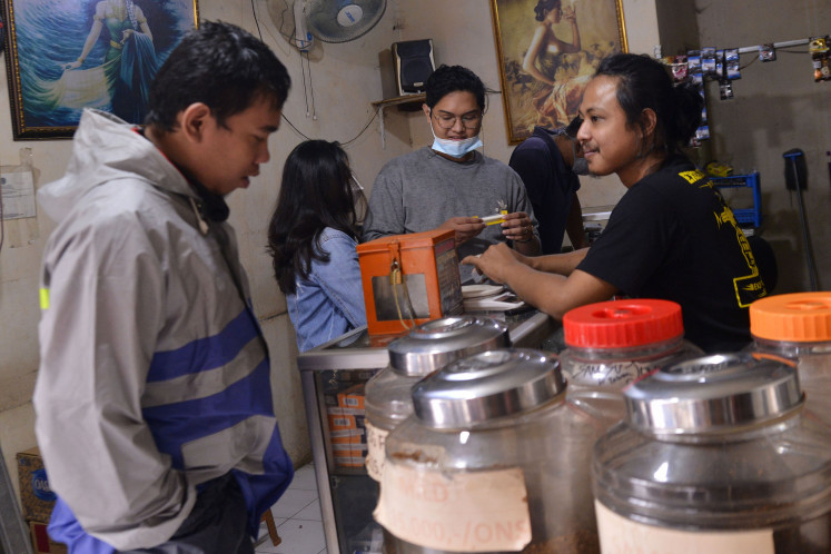 A tobacco shop keeper at the 'Bakobakotok' kiosk in Depok explains the characteristic of the tingwe tobacco to a customer 
