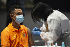 Indonesian national soccer player Miftahul Hamdi (left) receives his first shot of COVID-19 vaccine during a national inoculation session held at Istora Senayan sports arena in Gelora Bung Karno, Jakarta, on Feb. 26. 