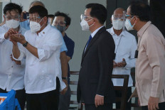 This handout photo taken on February 28, 2021 and received from the Presidential Communications Operations Office (PCOO) shows Philippine President Rodrigo Duterte (2nd left) looking at a vial of the Sinovac vaccine, after a plane transporting the first batch of the vaccine arrived abroad a Chinese air force plane, at Villamor air base in Manila. 