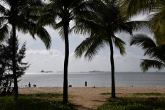 A woman carries a baby on the beach in Sanya on China's tropical Hainan Island on December 8, 2018. 