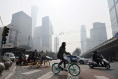 People cross a road on a polluted day in Beijing on October 10, 2020. 