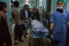 Hospital workers and relatives shift the body of one of the three female media workers shot to death in two separate attacks, at a hospital in Jalalabad on March 2.
